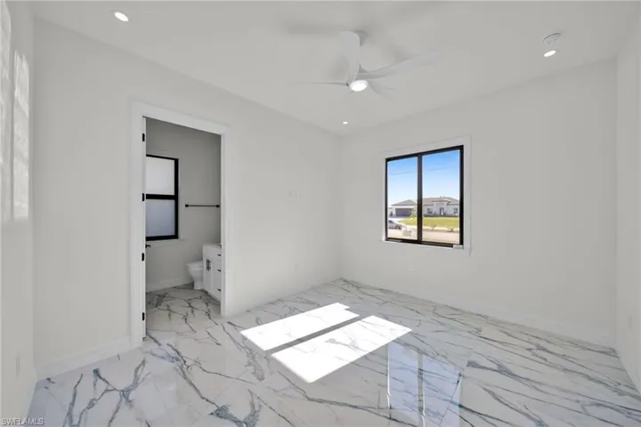 Unfurnished bedroom featuring light marble finish floors, a ceiling fan, recessed lighting, and connected bathroom