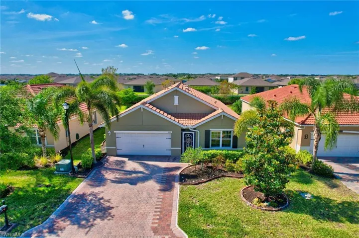 View of front facade featuring a tile roof, decorative driveway, an attached garage, and a front lawn