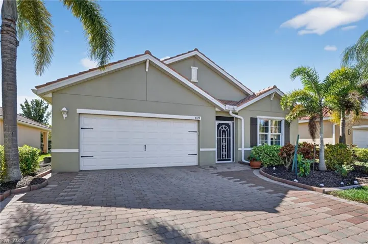 Single story home with decorative driveway, stucco siding, and an attached garage