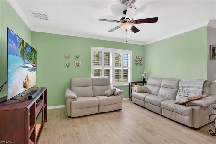 Living room featuring light wood-style flooring, crown molding, and ceiling fan
