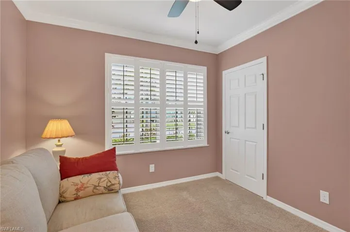 Living area with light carpet, crown molding, and a ceiling fan
