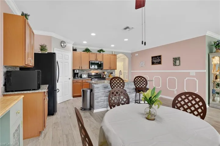 Dining room featuring arched walkways, ornamental molding, light wood-style floors, recessed lighting, and ceiling fan