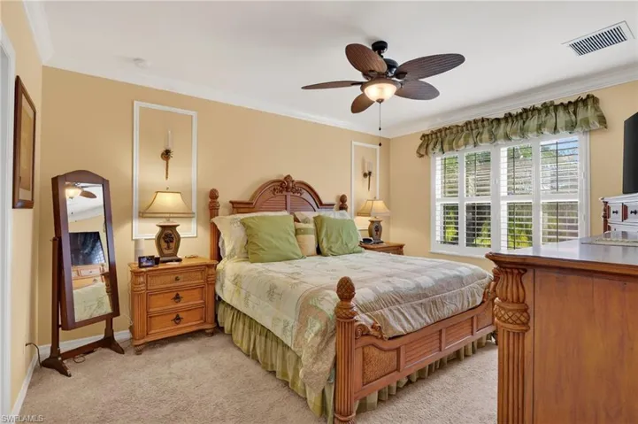 Bedroom featuring ornamental molding, light carpet, and a ceiling fan