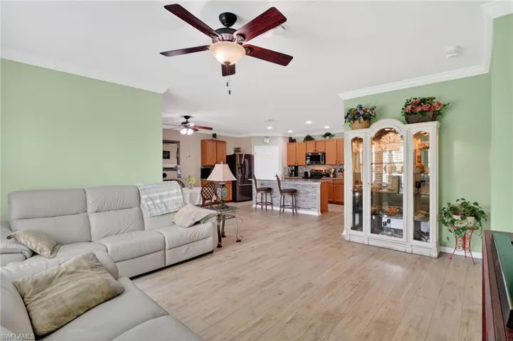 Living room featuring light wood-style flooring, crown molding, and a ceiling fan