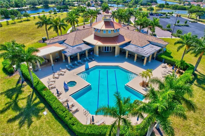 Community pool featuring a hot tub, a lawn, a patio, and a water view