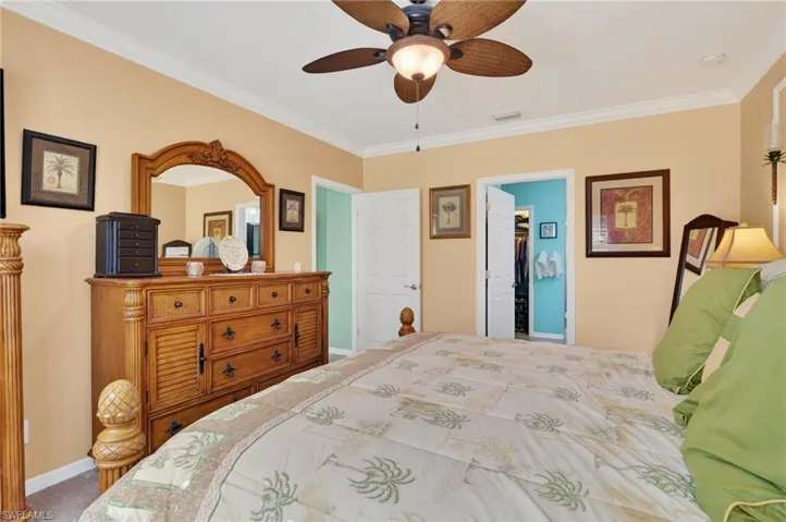 Carpeted bedroom featuring ornamental molding and ceiling fan
