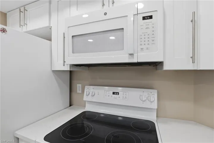 Kitchen view of white appliances, white cabinets, and light stone countertops