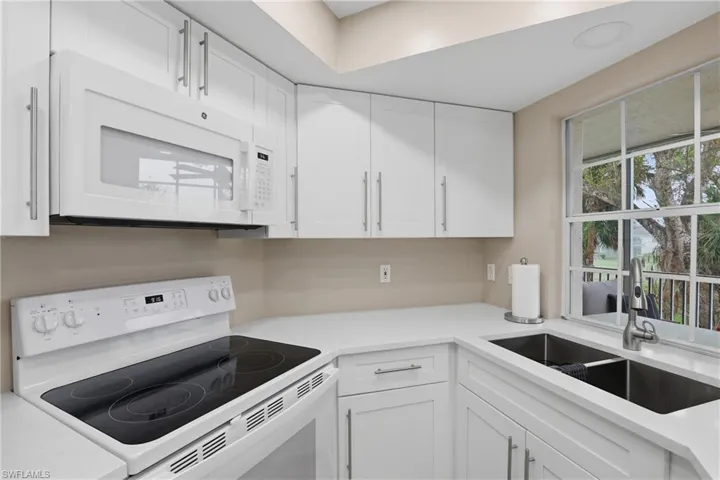 Kitchen featuring white appliances, white cabinets, and light stone countertops