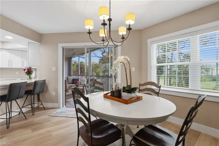 Dining space with suspended lighting, light wood-style floors, and healthy amount of natural light