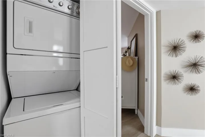 Laundry area with stacked washer and dryer and light wood-style flooring