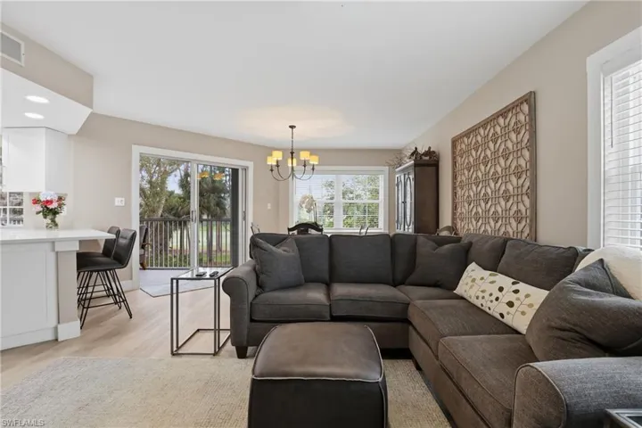 Living area with suspended lighting and light wood-style flooring