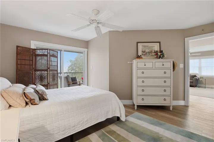 Bedroom with light wood-type flooring, access to exterior, a ceiling fan, and multiple windows