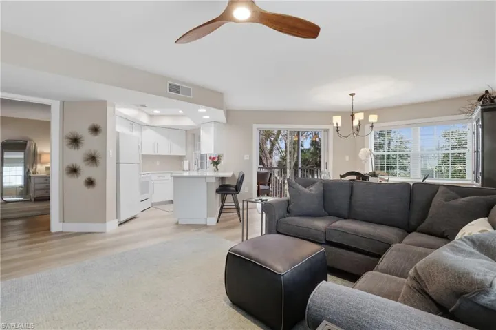 Living room featuring a ceiling fan, suspended lighting, and light wood-style flooring