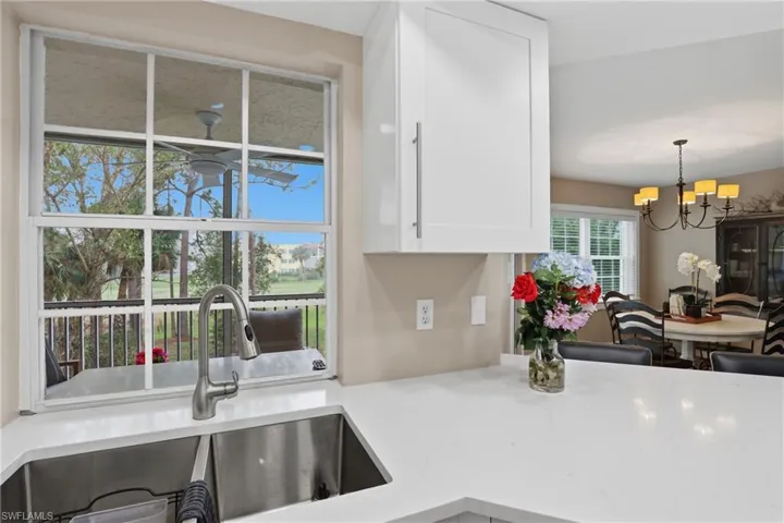 Kitchen with light stone counters, suspended lighting, and white cabinetry