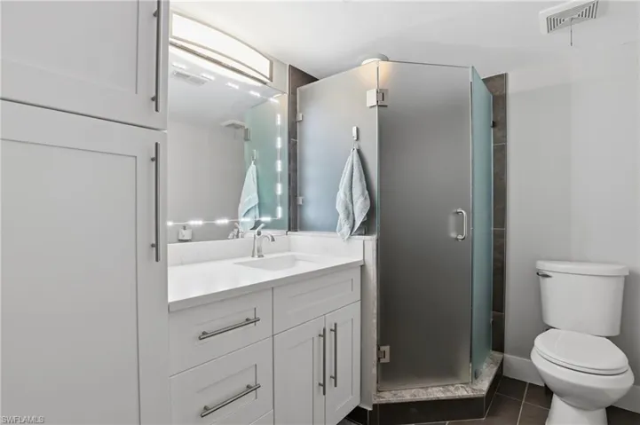 Full bath featuring vanity, a stall shower, and dark tile patterned flooring