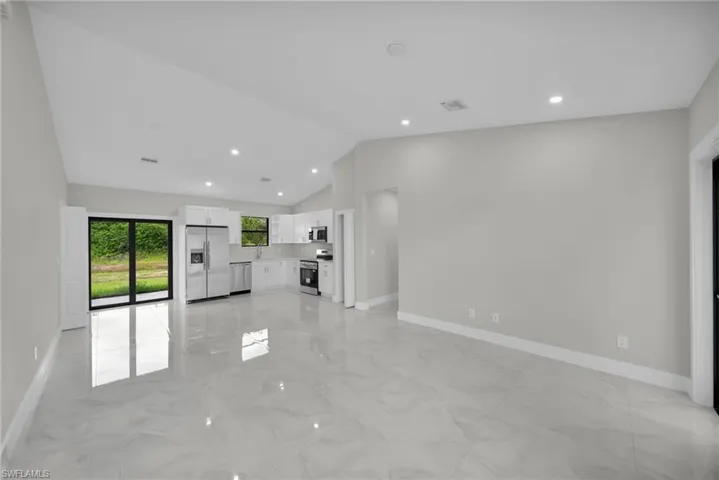 Open-concept living space featuring high vaulted ceilings, recessed lighting, and large format polished tile flooring