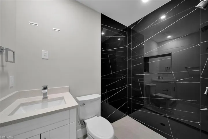Modern bathroom featuring a white vanity with a light-toned countertop, a contemporary sink, and a sleek chrome faucet