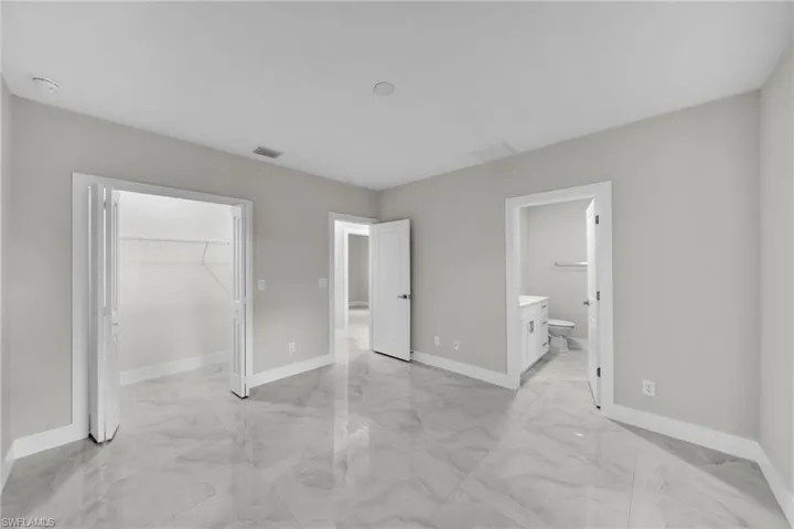 Spacious room with light gray walls and large format marble-look tile flooring