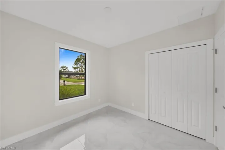 Light gray walls with white baseboards complement the large format tile flooring