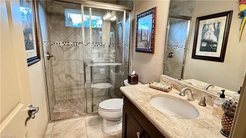 Bathroom with tile patterned flooring, vanity, an enclosed shower, and toilet