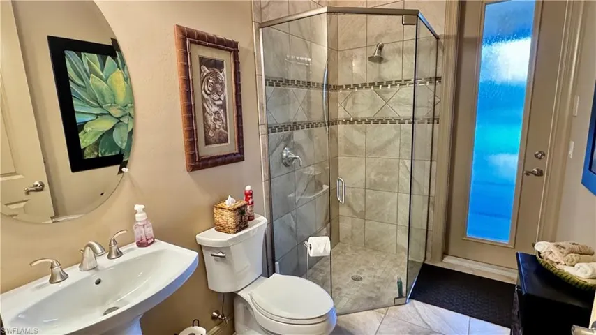 Bathroom with tile patterned floors, toilet, a shower with door, and sink