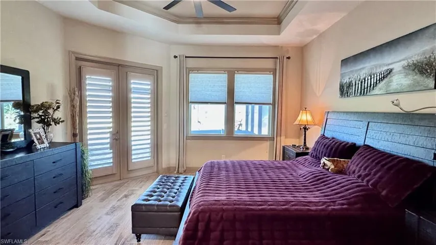 Bedroom with a raised ceiling, crown molding, ceiling fan, access to exterior, and light hardwood / wood-style floors