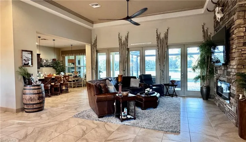 Living room with plenty of natural light, a raised ceiling, crown molding, and french doors
