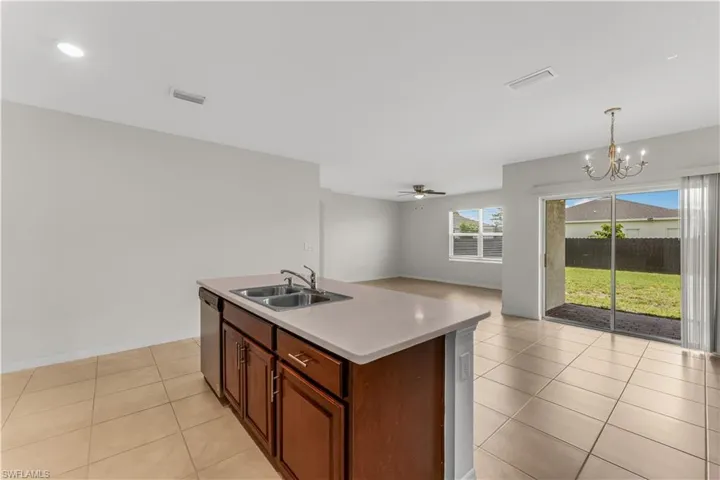 Kitchen with light tile patterned flooring, a chandelier, ceiling fan, open floor plan, and light countertops