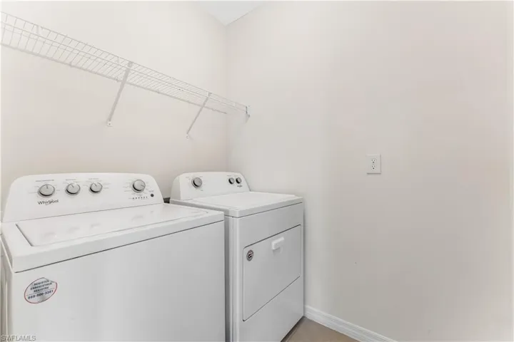 Laundry area with washing machine and clothes dryer and baseboards