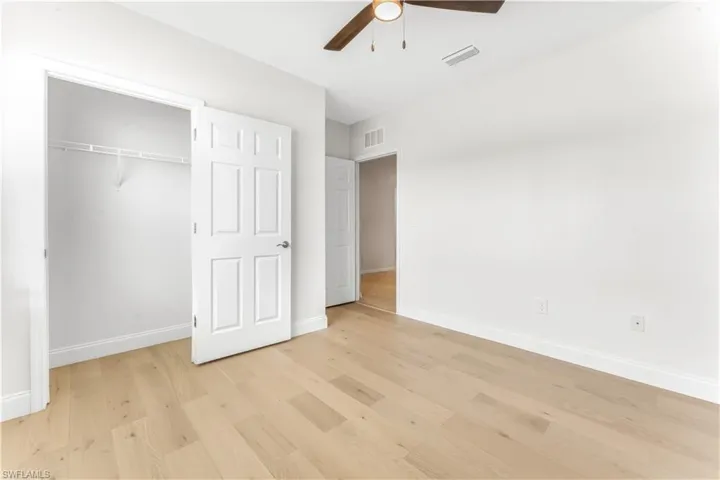Unfurnished bedroom with light wood-type flooring, a closet, and a ceiling fan