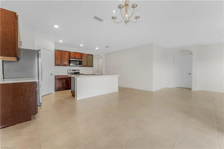 Kitchen with stainless steel appliances, arched walkways, light tile patterned flooring, recessed lighting, and a chandelier