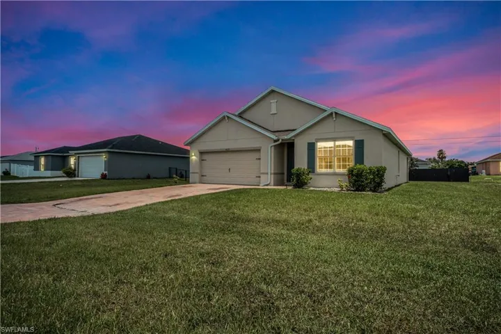 Ranch-style home with concrete driveway, an attached garage, a lawn, and stucco siding