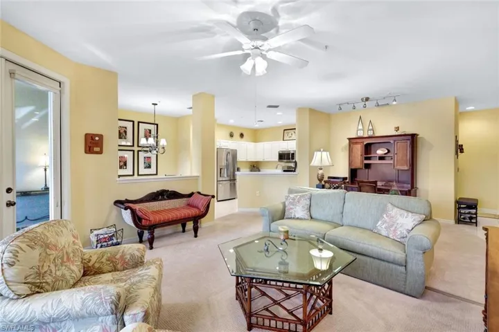 Carpeted living room with ceiling fan with notable chandelier