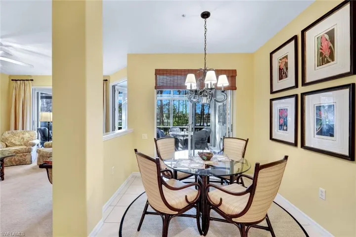 Carpeted dining room with ceiling fan with notable chandelier
