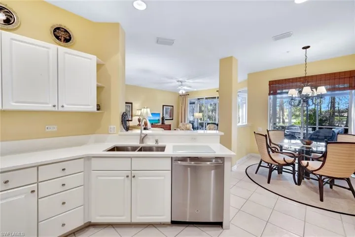 Kitchen featuring white cabinetry, dishwasher, sink, kitchen peninsula, and pendant lighting