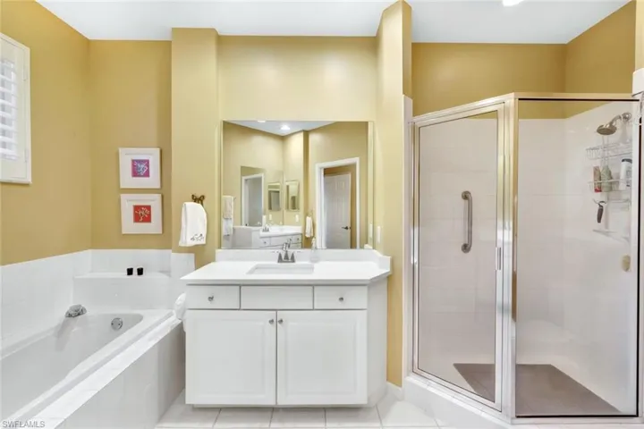 Bathroom with tile patterned flooring, vanity, and plus walk in shower