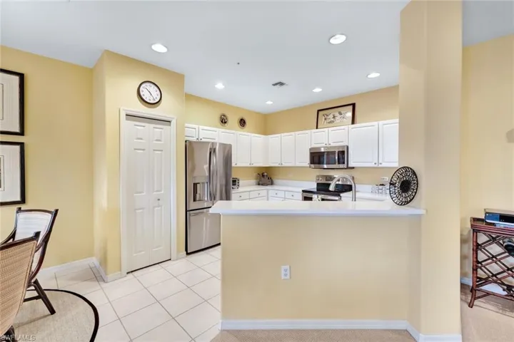 Kitchen featuring white cabinets, light tile patterned floors, stainless steel appliances, and kitchen peninsula