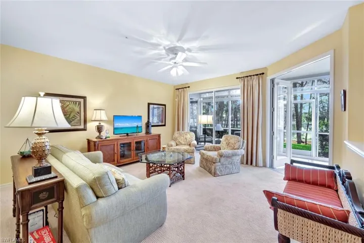 Carpeted living room featuring ceiling fan and a wealth of natural light