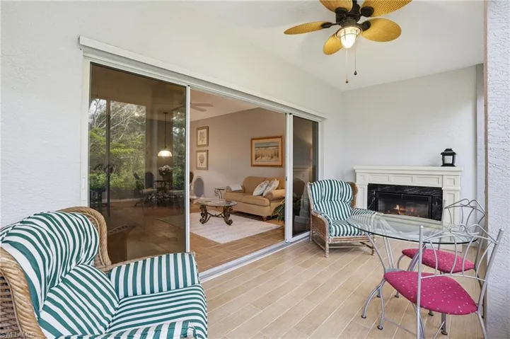 Sunroom / solarium with ceiling fan, a high end fireplace, and a patio