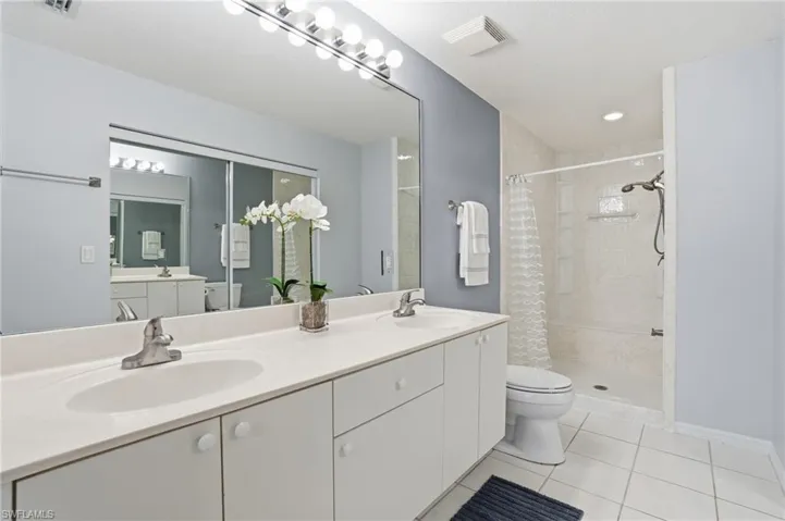 Full bathroom featuring double vanity, a shower stall, and light tile patterned floors