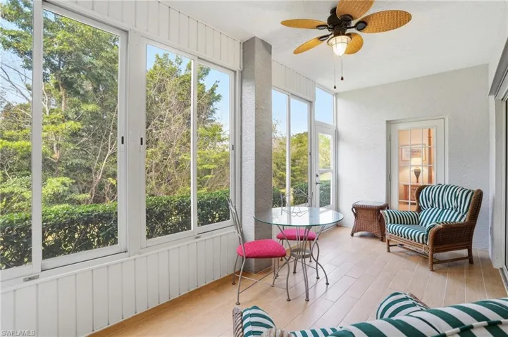 Sunroom / solarium with a ceiling fan, a textured wall, wood finished floors, and outdoor dining space