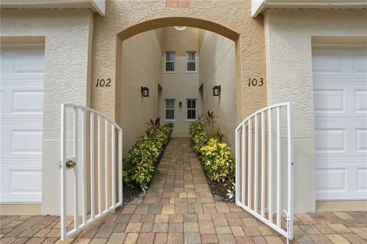 Doorway to property featuring stucco siding and a gate