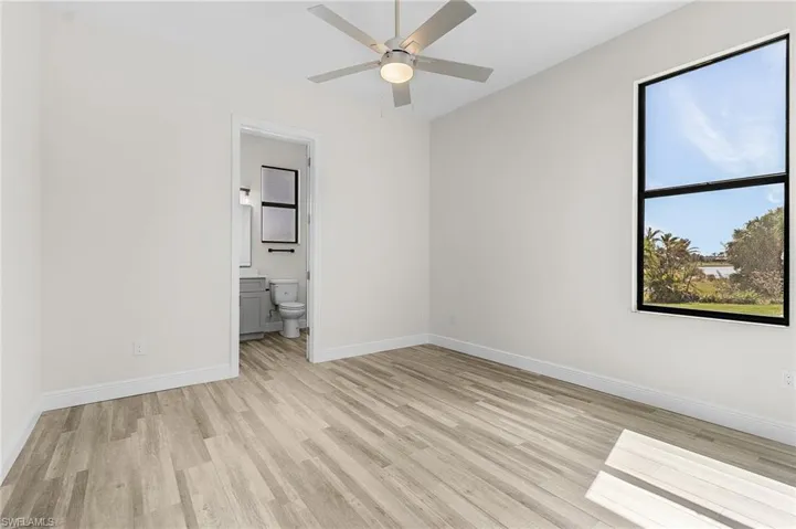 Unfurnished bedroom featuring light hardwood / wood-style flooring, ensuite bath, and ceiling fan