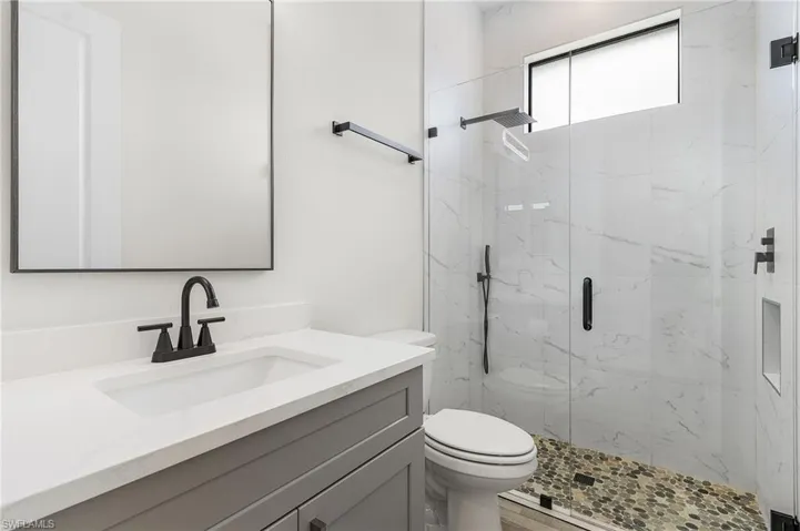 Bathroom featuring vanity, hardwood / wood-style flooring, toilet, and an enclosed shower