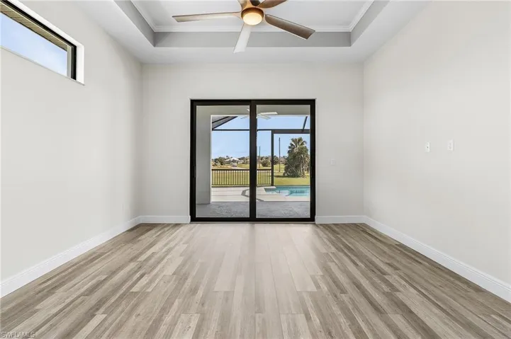 Unfurnished room with ornamental molding, light hardwood / wood-style flooring, ceiling fan, and a raised ceiling