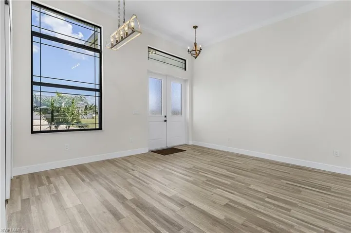 Entryway with crown molding, light hardwood / wood-style floors, a notable chandelier, and a healthy amount of sunlight