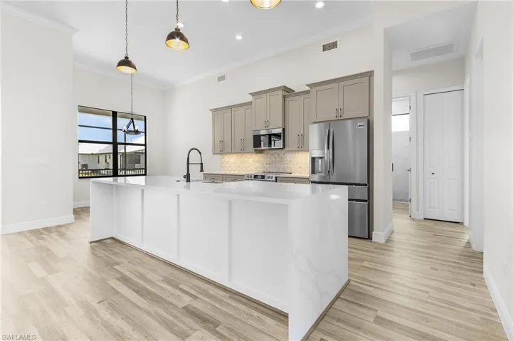 Kitchen with ornamental molding, sink, appliances with stainless steel finishes, and light hardwood / wood-style flooring