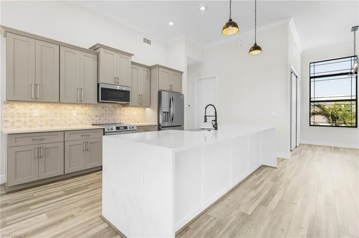 Kitchen with pendant lighting, sink, light hardwood / wood-style flooring, and stainless steel appliances