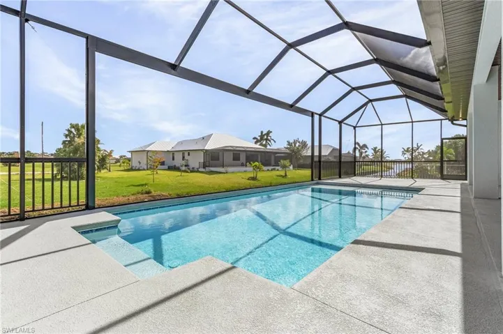 View of pool featuring a patio area, a yard, and glass enclosure