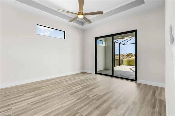 Empty room featuring light hardwood / wood-style floors, ornamental molding, a tray ceiling, and ceiling fan